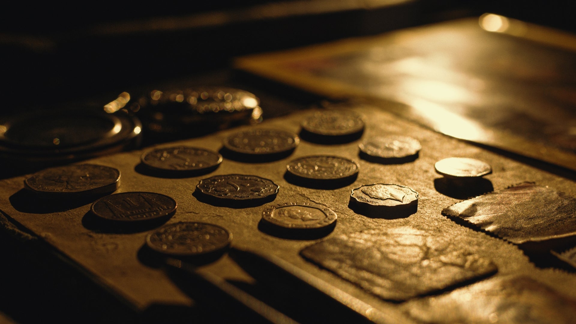 Collection of coins on a metal surface with a warm, amber tone.